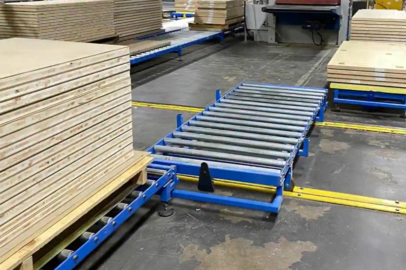 Sistema transportador de rodillos por gravedad para el transporte de pilas de láminas de madera