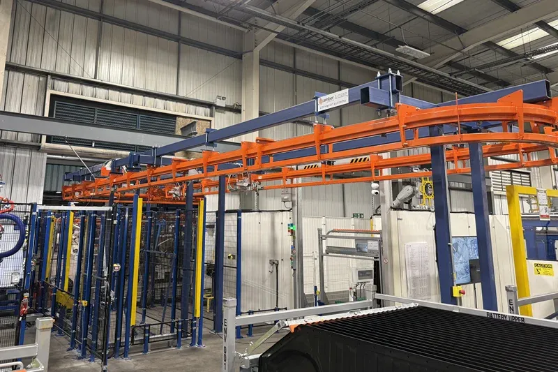 Estructura de soporte y riel para transportador aéreo MCM Autotrack MCM Autotrack orange overhead conveyor track supported by blue steel framework in an automotive production facility